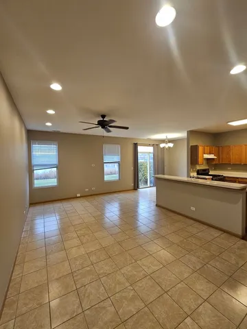 a view of an empty room and a kitchen with a sink