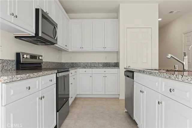 a kitchen with granite countertop white cabinets and stainless steel appliances