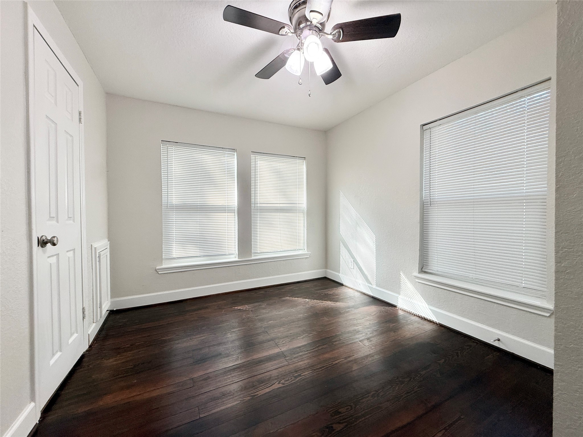 620 East Magnolia Street Angleton, TX 77515 - Photo 11 of 20 an empty room with wooden floor chandelier fan and windows