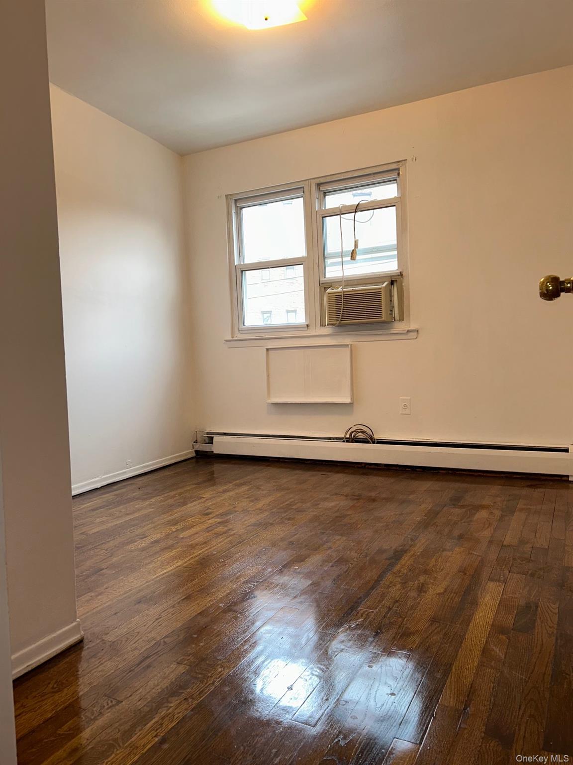 142-22 Pershing Crescent Queens, NY 11435 - Photo 9 of 11 an empty room with wooden floor and windows