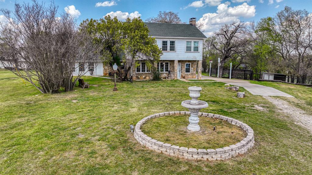 7350 Briar Road Azle, TX 76020 - Photo 1 of 1 Colonial house with driveway, a front yard, stone siding, a chimney, and fence
