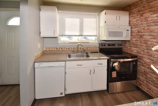 a kitchen with stainless steel appliances granite countertop a stove a sink and a microwave