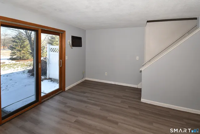 a view of an empty room with wooden floor and doors