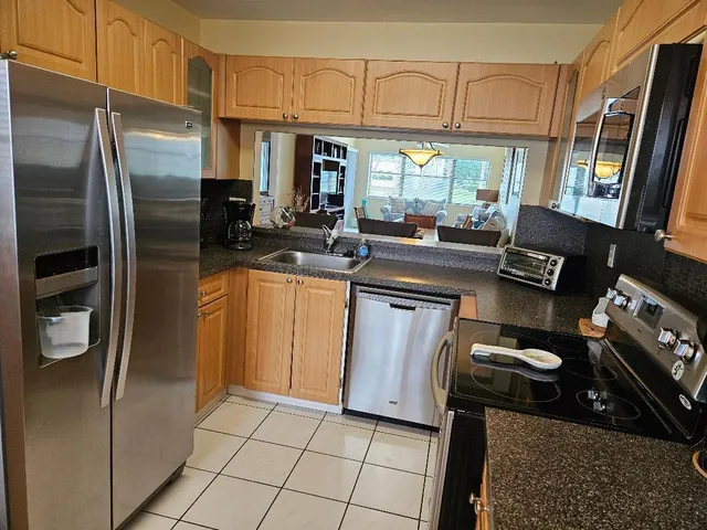 a kitchen with stainless steel appliances granite countertop a refrigerator a stove and a sink