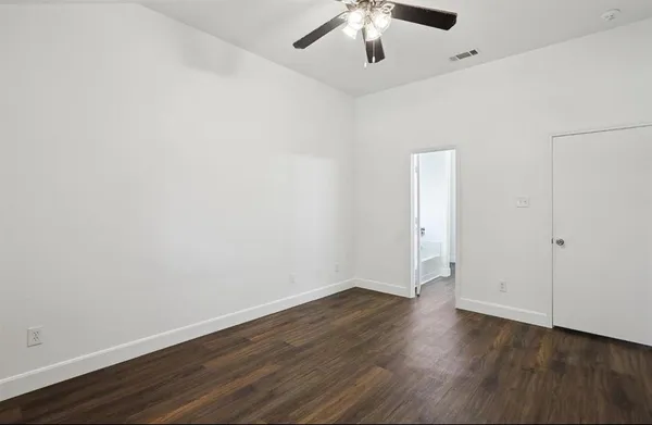 an empty room with wooden floor and ceiling fan