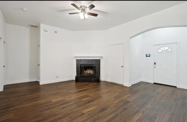 a view of an empty room with wooden floor and a fireplace