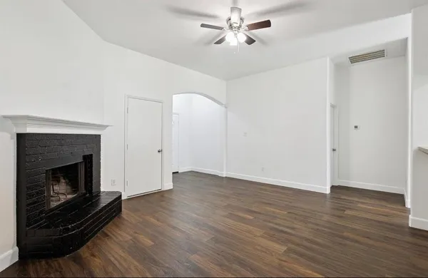 a view of an empty room with wooden floor fireplace and a window