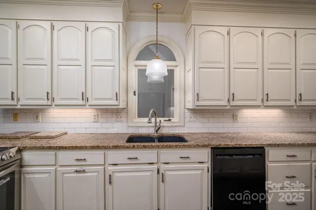 a kitchen with white cabinets and sink
