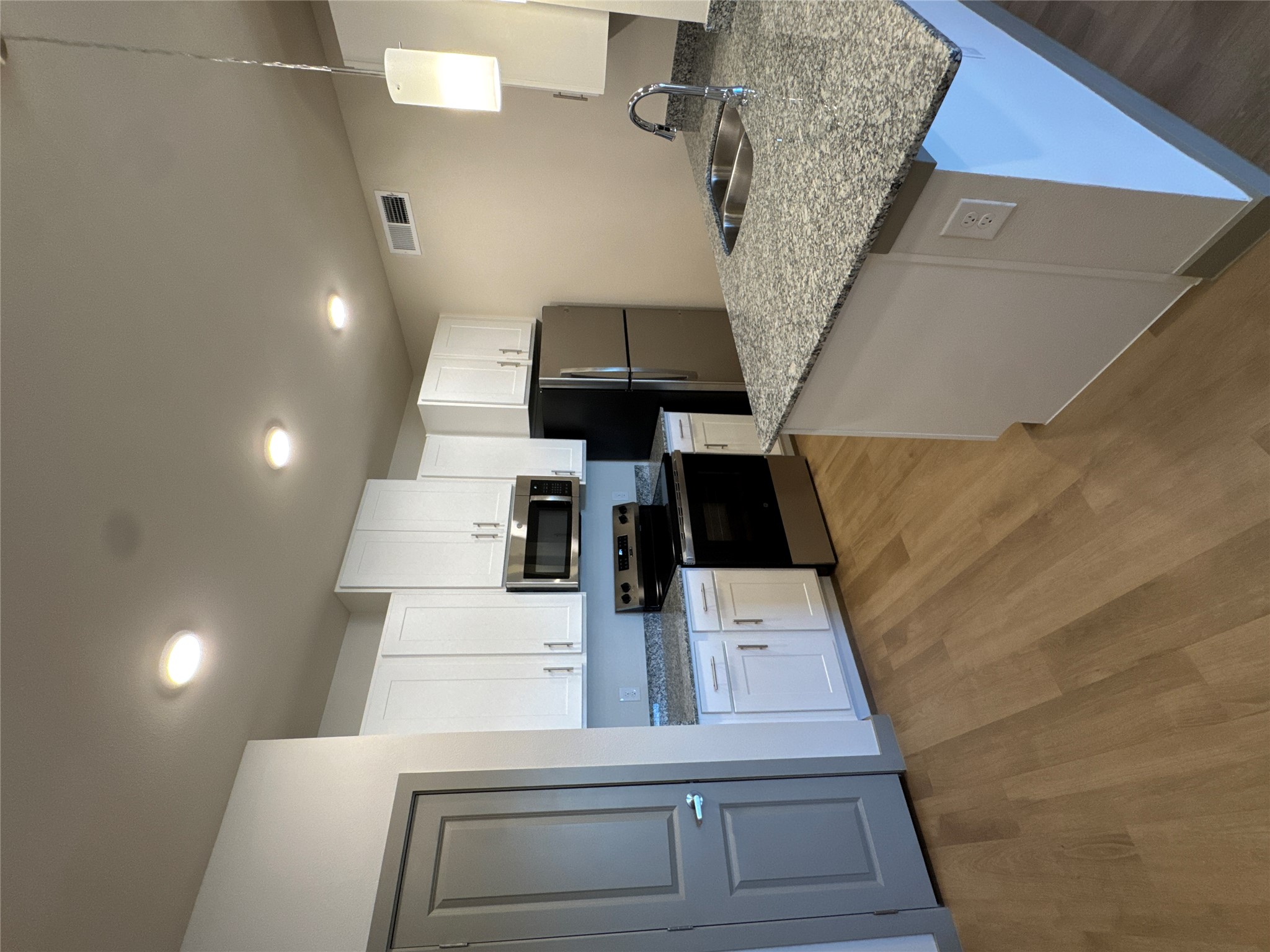 691 Union Chapel Road, Unit B1 Cedar Creek, TX 78612 - Photo 4 of 28 Kitchen featuring light stone counters, appliances with stainless steel finishes, white cabinetry, hanging light fixtures, and light wood style floors