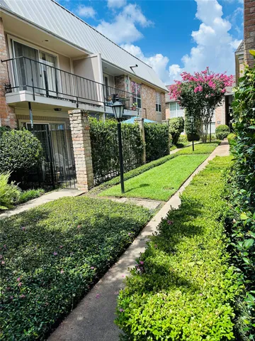 a view of a house with brick walls and a yard with plants