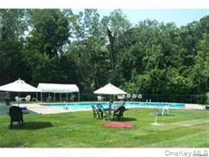 a view of a swimming pool with a table and chairs under an umbrella