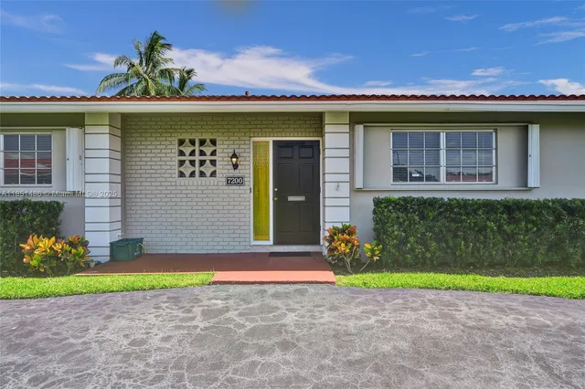 a view of a house with a yard and potted plants