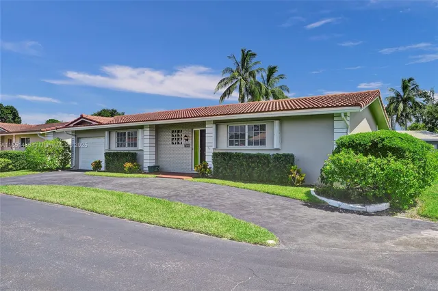 a front view of a house with a yard and potted plants