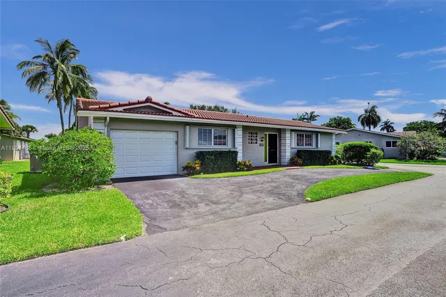 a view of a house with a yard and large tree