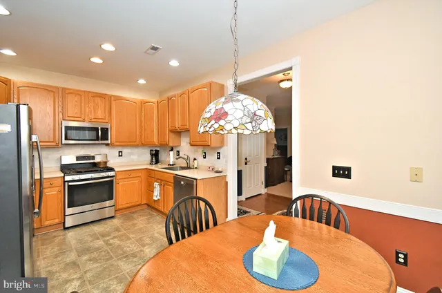a kitchen with stainless steel appliances granite countertop a sink dishwasher a stove a refrigerator with a dining table and chairs with wooden floor