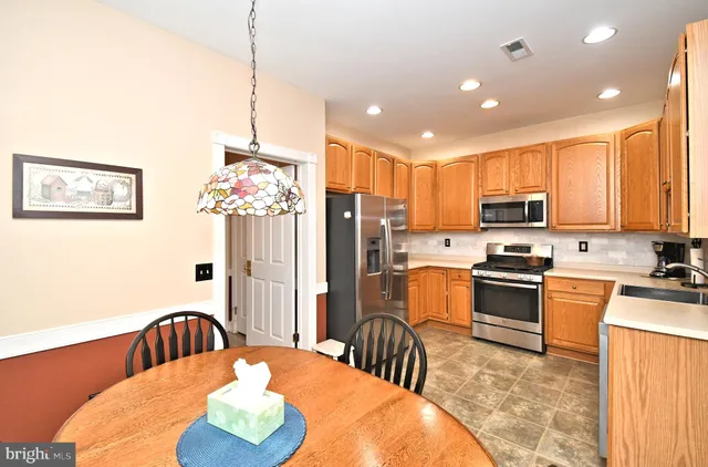 a kitchen with stainless steel appliances granite countertop a refrigerator a stove top oven a sink dishwasher and wooden cabinets