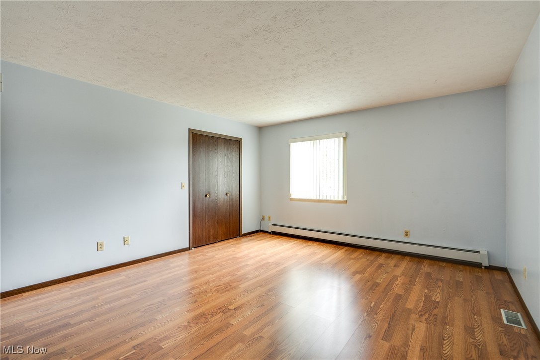 308 Guy's Run Road Akron, OH 44319 - Photo 35 of 44 Spare room with a baseboard heating unit, a textured ceiling, baseboards, visible vents, and wood finished floors