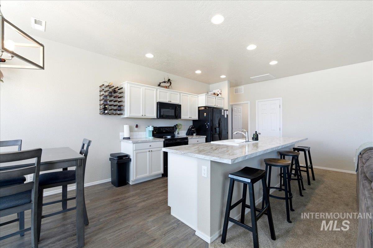843 Southwest Levant Way Mountain Home, ID 83647 - Photo 9 of 45 Kitchen with light countertops, a kitchen breakfast bar, white cabinetry, black appliances, and an island with sink