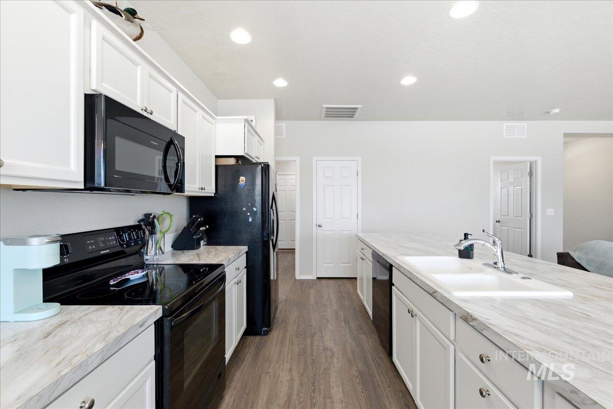 843 Southwest Levant Way Mountain Home, ID 83647 - Photo 10 of 45 Kitchen with black appliances, light countertops, white cabinets, dark wood-style floors, and recessed lighting