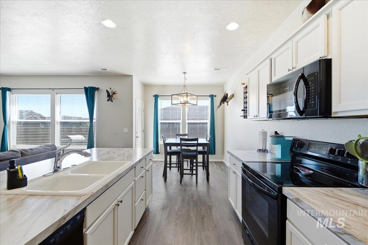 843 Southwest Levant Way Mountain Home, ID 83647 - Photo 11 of 45 Kitchen featuring black appliances, white cabinets, light countertops, and a textured ceiling