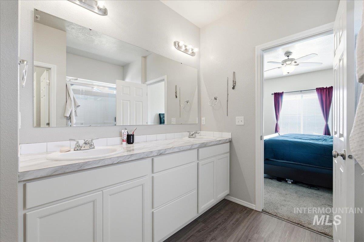 843 Southwest Levant Way Mountain Home, ID 83647 - Photo 14 of 45 Full bathroom featuring ensuite bath, double vanity, dark wood-type flooring, a shower stall, and ceiling fan
