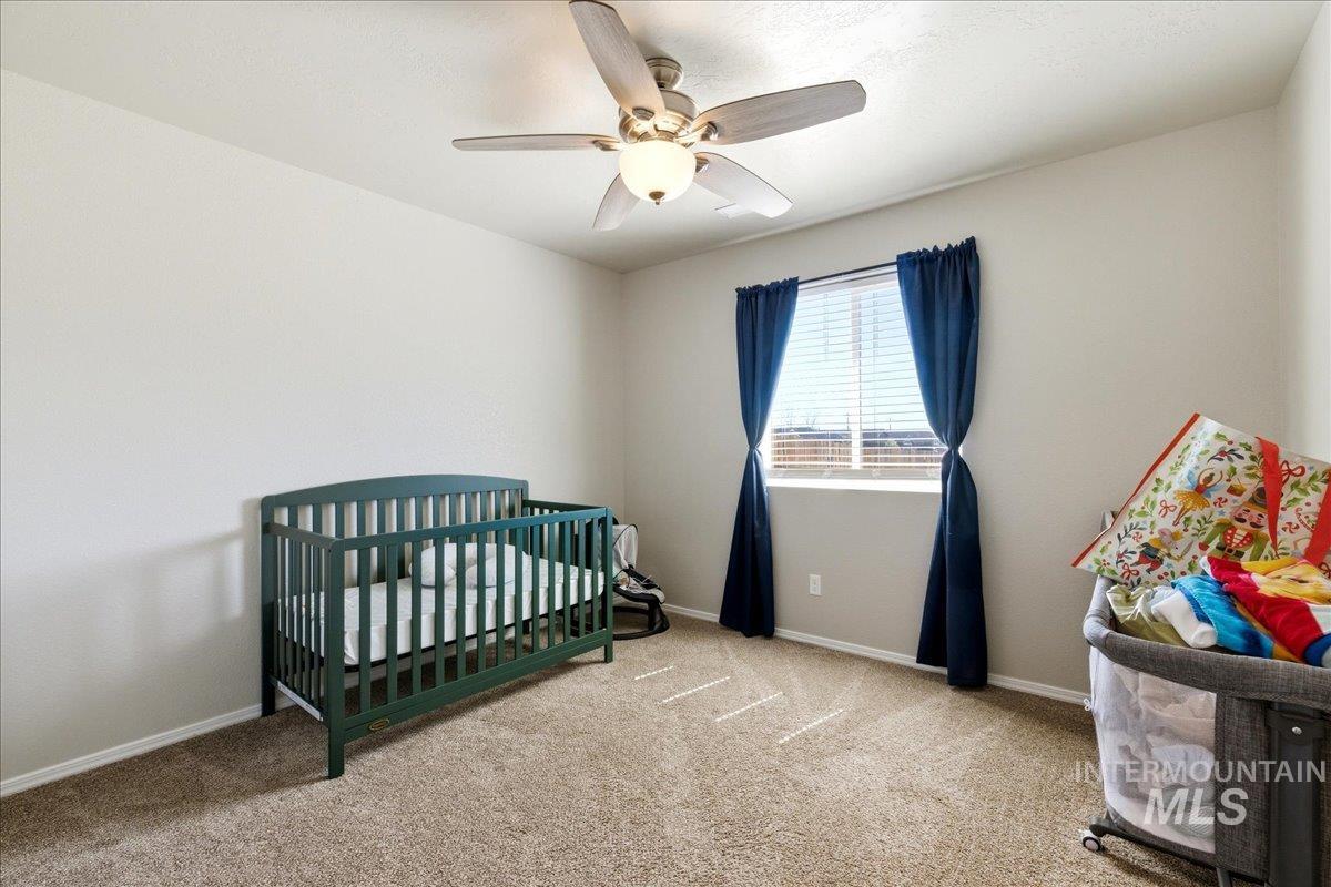 843 Southwest Levant Way Mountain Home, ID 83647 - Photo 21 of 45 Bedroom featuring a crib, light colored carpet, and a ceiling fan