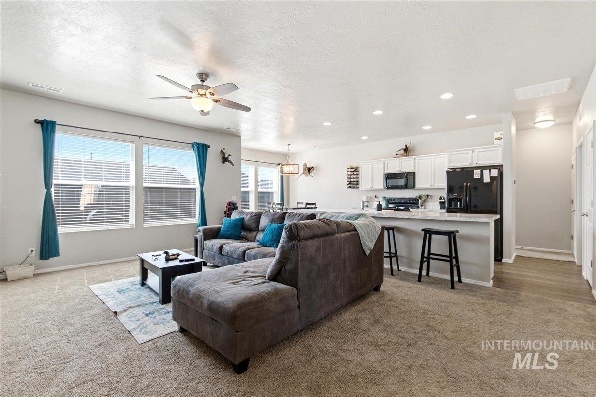 843 Southwest Levant Way Mountain Home, ID 83647 - Photo 4 of 45 Living area with light carpet, a ceiling fan, recessed lighting, and a textured ceiling