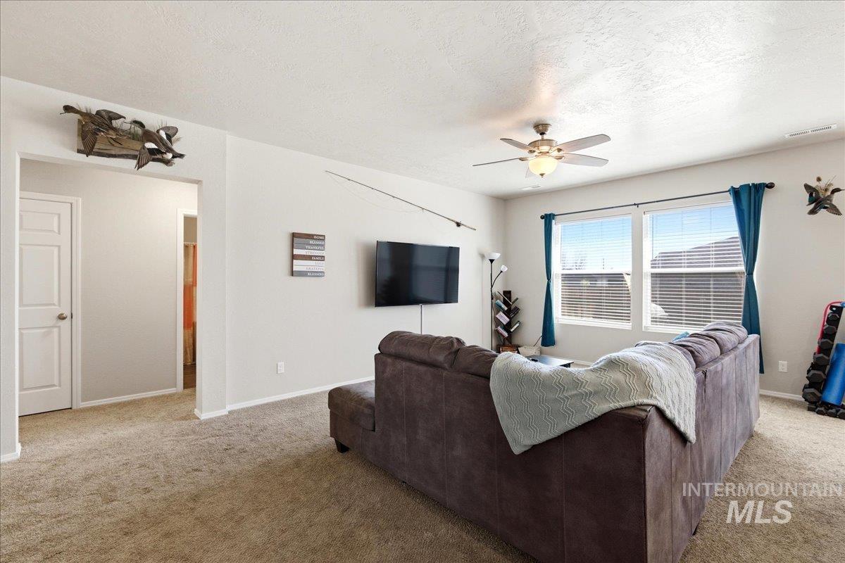 843 Southwest Levant Way Mountain Home, ID 83647 - Photo 5 of 45 Living area with a ceiling fan, light carpet, and a textured ceiling