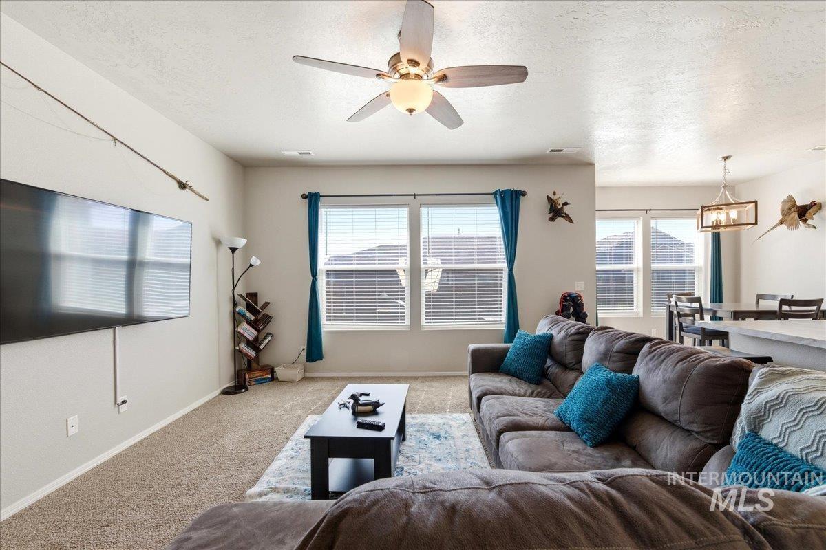 843 Southwest Levant Way Mountain Home, ID 83647 - Photo 8 of 45 Living room with carpet, a ceiling fan, a textured ceiling, and hanging lights