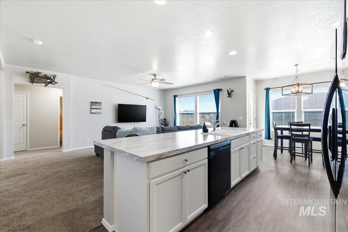 843 Southwest Levant Way Mountain Home, ID 83647 - Photo 44 of 45 Kitchen with light countertops, open floor plan, a center island with sink, white cabinetry, and black appliances