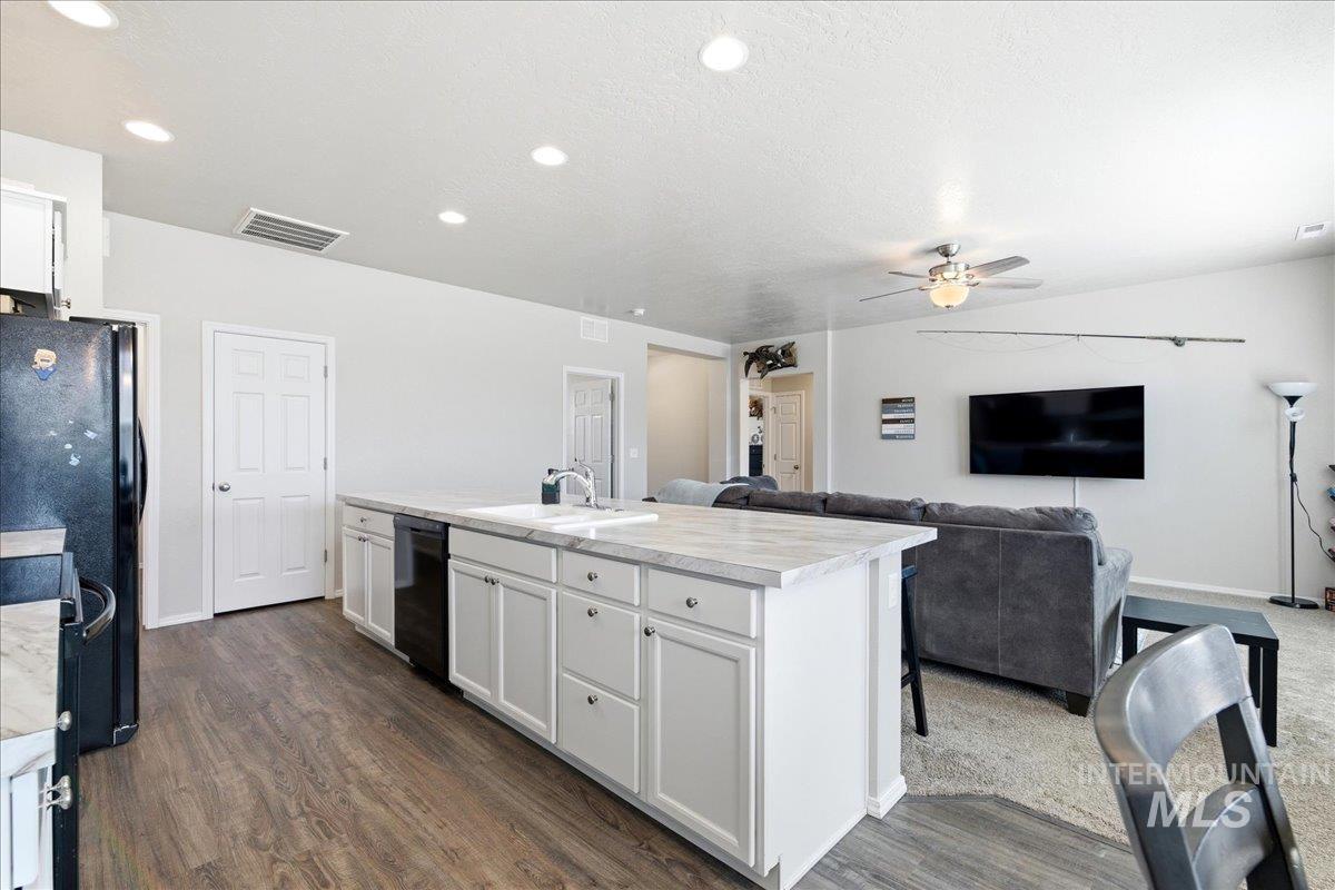 843 Southwest Levant Way Mountain Home, ID 83647 - Photo 45 of 45 Kitchen with light countertops, white cabinets, open floor plan, a kitchen island with sink, and recessed lighting