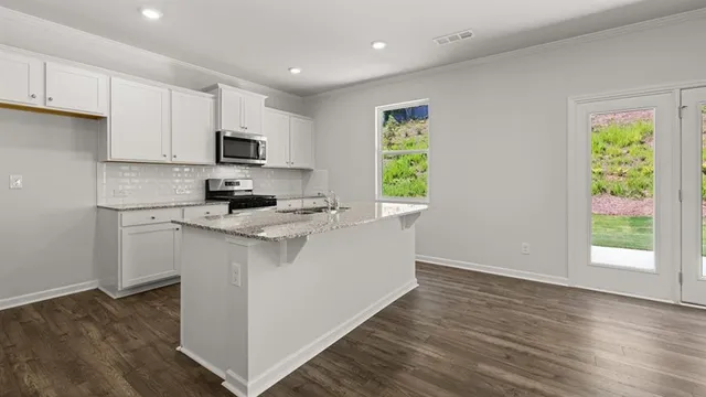 a kitchen with stainless steel appliances granite countertop a stove a sink and a microwave