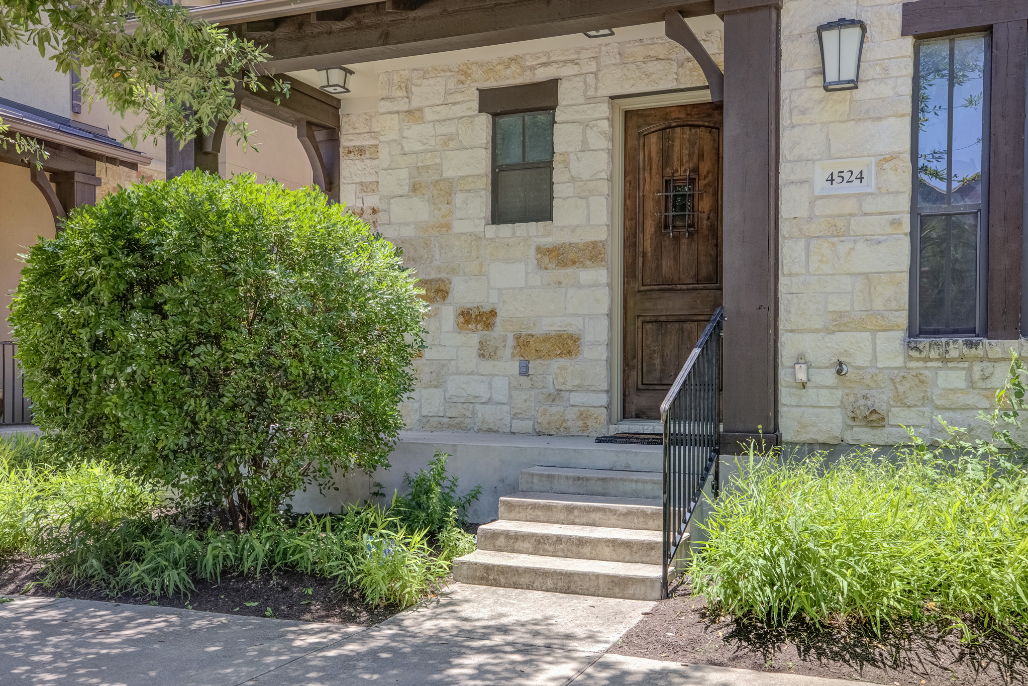 4524 Berkman Drive Austin, TX 78723 - Photo 2 of 38 Stone facade exterior with a prominent wood entry door featuring an iron grille