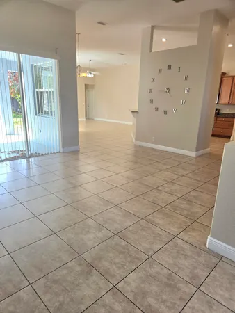 an empty room with wooden floor chandelier fan and windows