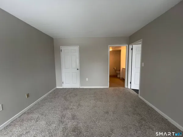 a view of an empty room with closet and a window