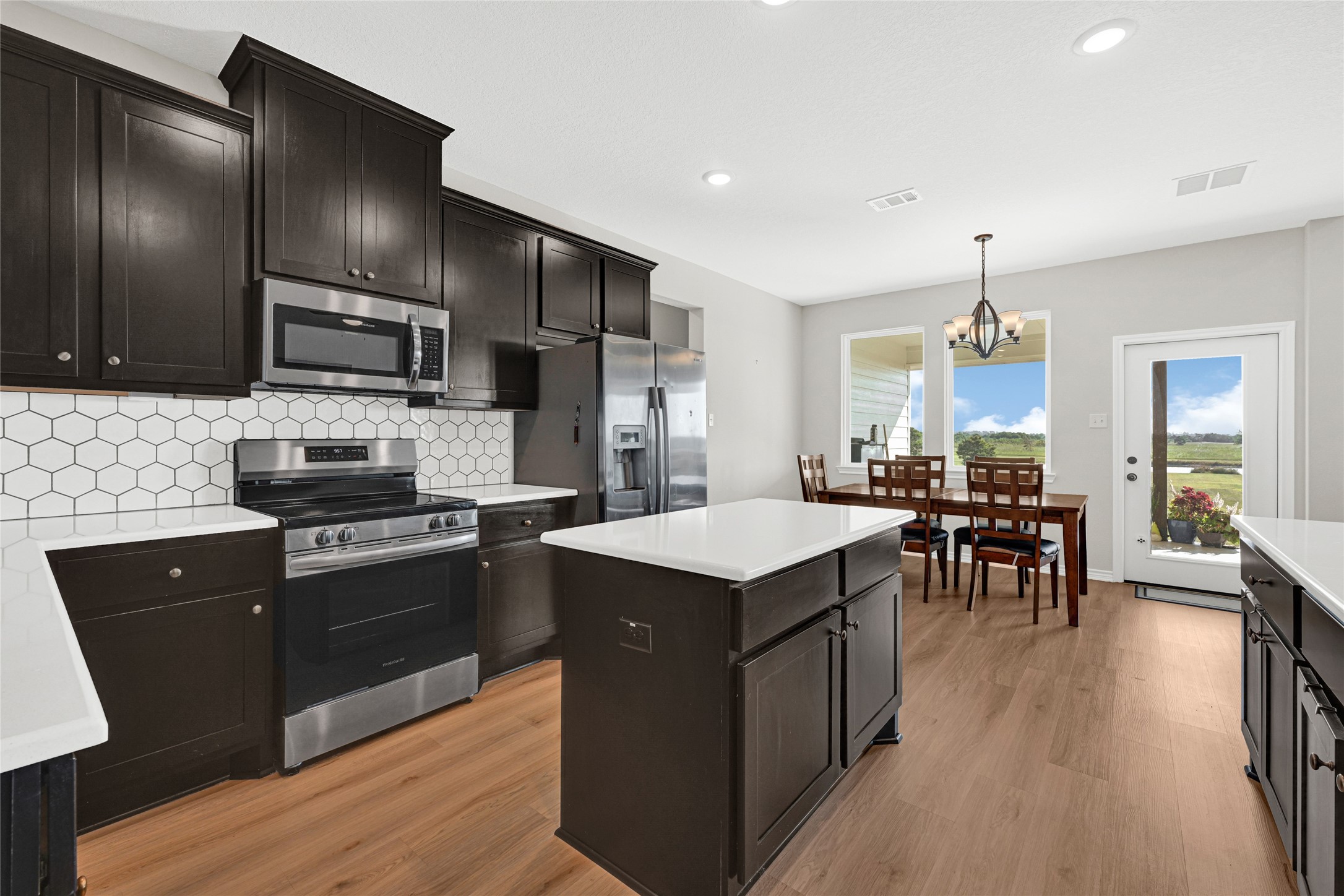 2256 West Bayshore Road Anahuac, TX 77514 - Photo 18 of 34 a kitchen with stainless steel appliances granite countertop wooden cabinets a refrigerator a stove a sink a dining table and chairs