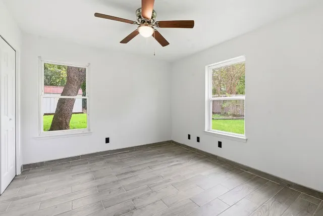 an empty room with windows and fan
