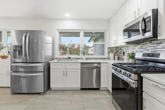 a kitchen with stainless steel appliances granite countertop a stove a refrigerator and a microwave