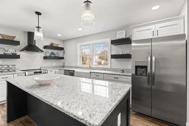 a kitchen with stainless steel appliances granite countertop a sink a refrigerator and a stove top oven