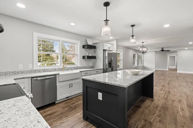 a kitchen with granite countertop cabinets stainless steel appliances a sink and a wooden floor
