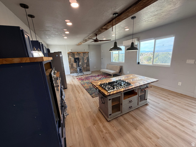 14183 High Mesa Loop Duchesne, UT 84021 - Photo 31 of 56 Kitchen with light wood-type flooring, a textured ceiling, a wood stove, freestanding refrigerator, and hanging light fixtures