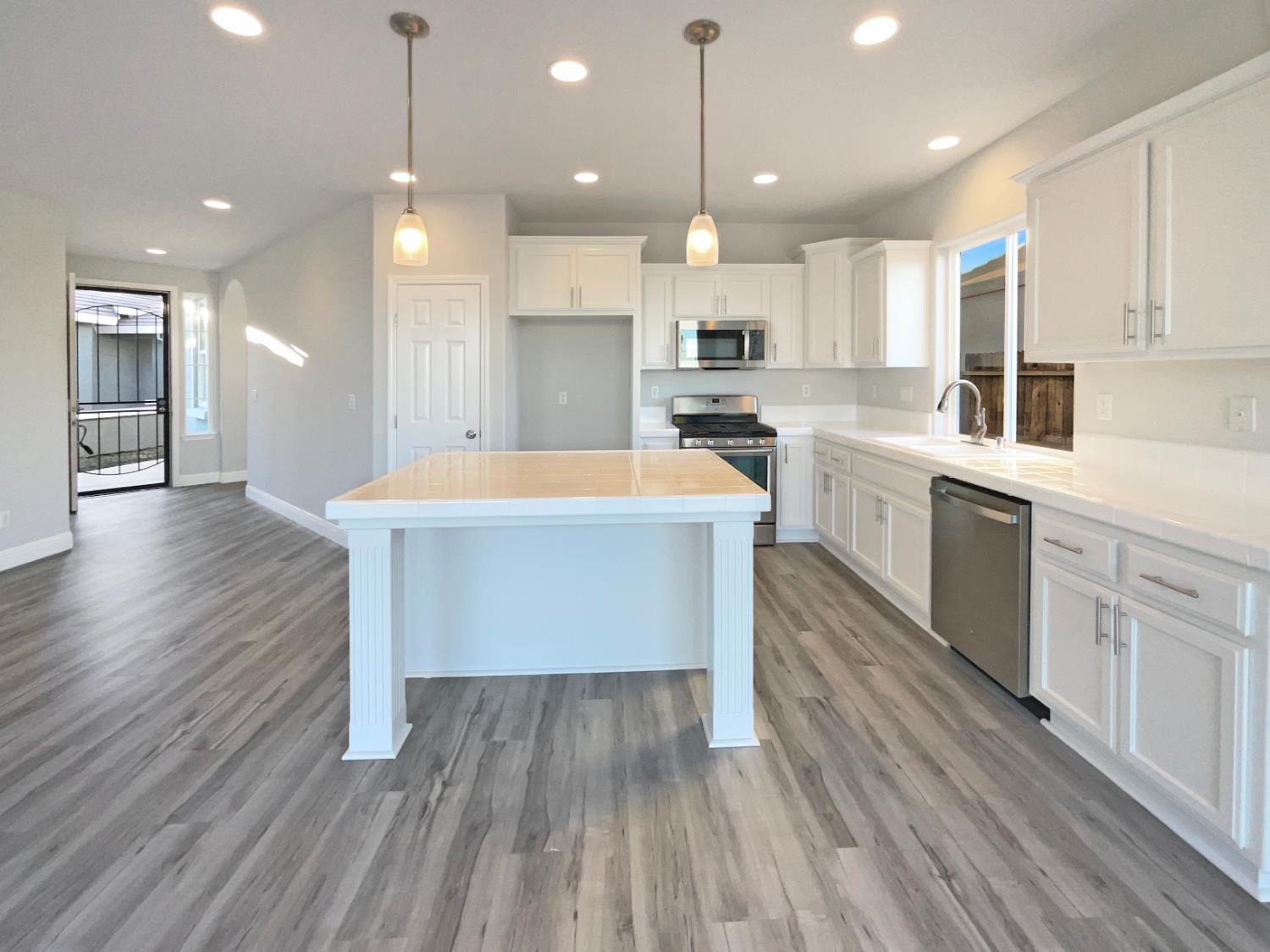 4087 Preserve Way Rancho Cordova, CA 95742 - Photo 13 of 24 a large kitchen with kitchen island a sink dishwasher a stove and white cabinets with wooden floor