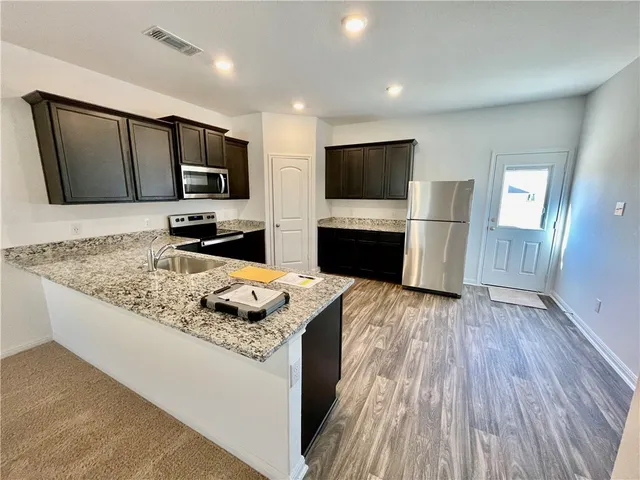 a kitchen with stainless steel appliances granite countertop a sink stove microwave and refrigerator