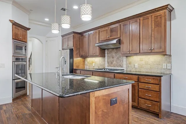 a kitchen with kitchen island granite countertop a sink cabinets and stainless steel appliances