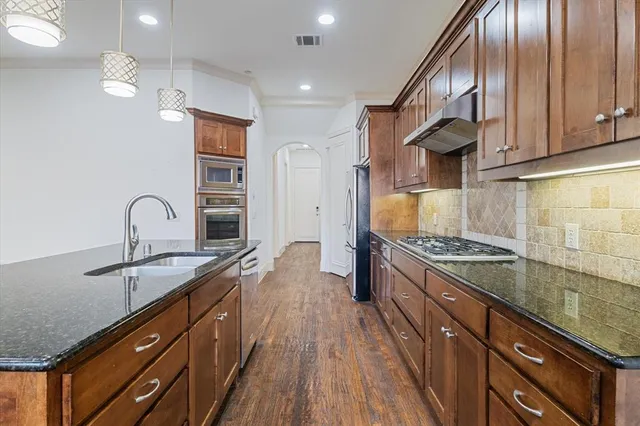 a kitchen with granite countertop a sink stainless steel appliances and cabinets