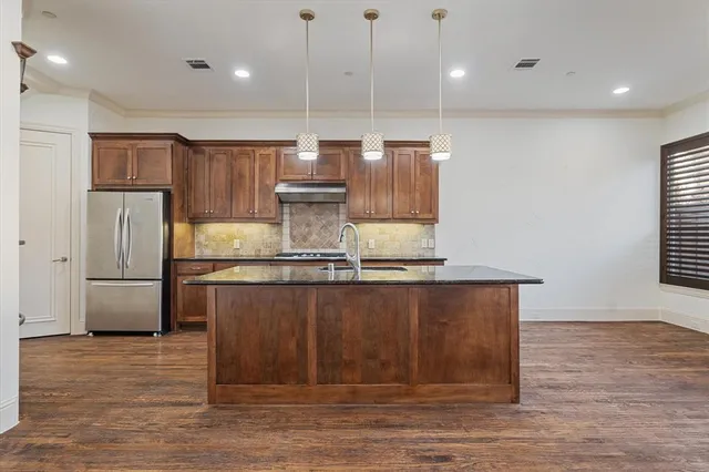 a kitchen with kitchen island a counter top a refrigerator a sink and a stove