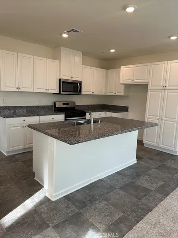 a kitchen with stainless steel appliances granite countertop a stove a sink and a microwave