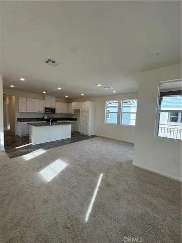 a view of empty room with kitchen and window