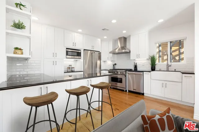 a kitchen with stainless steel appliances kitchen island granite countertop a sink and a refrigerator