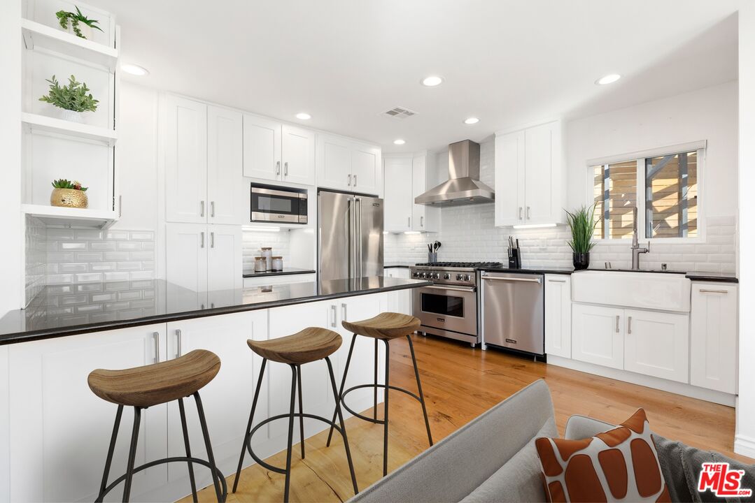 1788 North Orange Grove Avenue Los Angeles, CA 90046 - Photo 4 of 20 a kitchen with stainless steel appliances kitchen island granite countertop a sink and a refrigerator